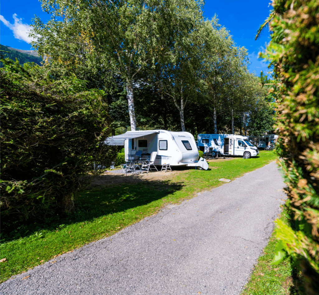 schmale Zufahrtsstraße zu den Stellplätzen der Kategorie 2. Ein Wohnwagen mit Vorzelt sowie ein Caravan sind zu sehen.