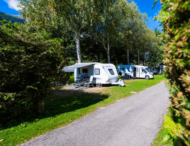 schmale Zufahrtsstraße zu den Stellplätzen der Kategorie 2. Ein Wohnwagen mit Vorzelt sowie ein Caravan sind zu sehen.